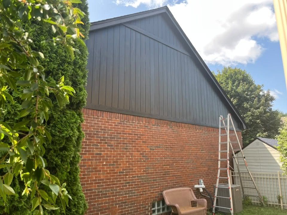 The finished gable end in deep black with the ladder still standing against the house at the end of the job