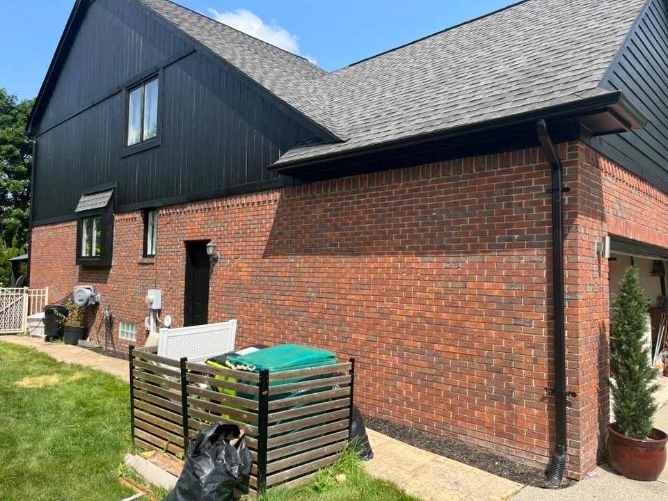 A Macomb County home after an exterior repaint, black siding and gables above red brick