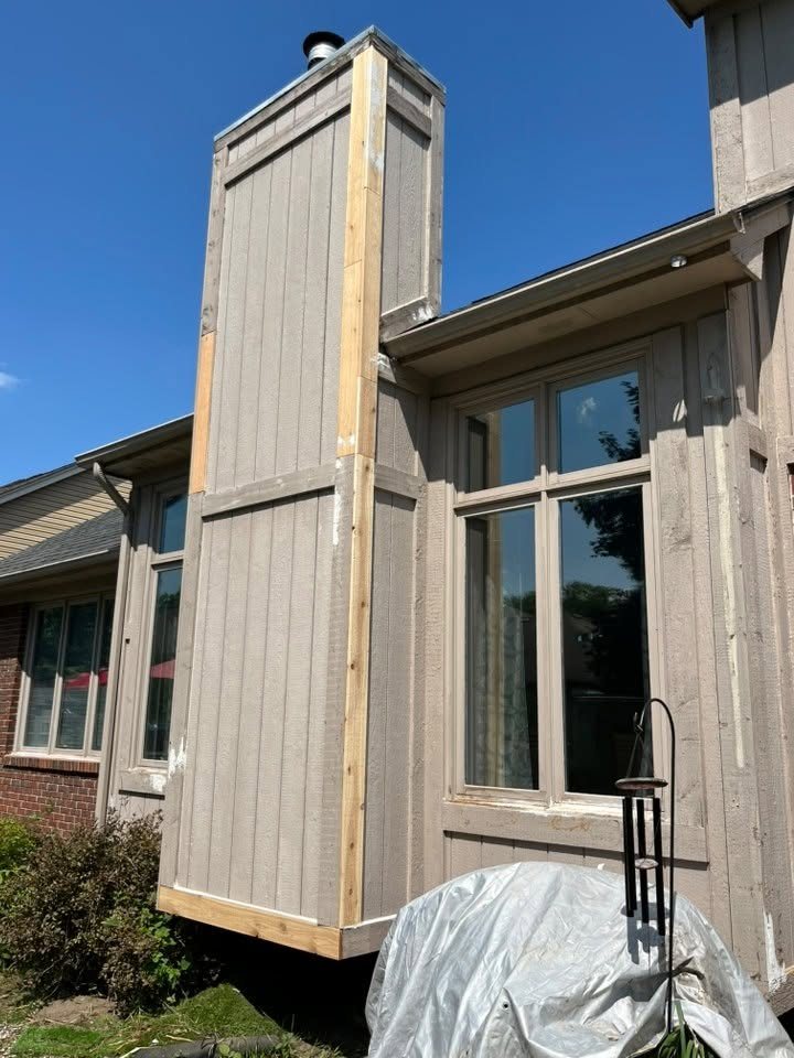 New bare cedar trim boards installed around a tall projecting gable and window before priming