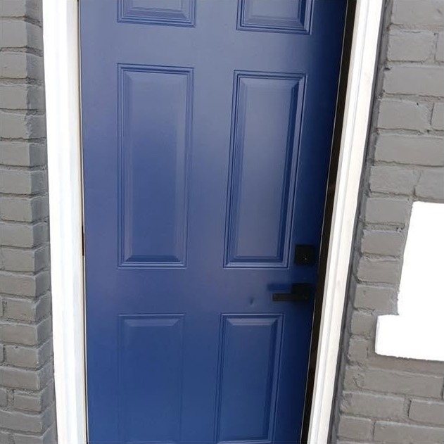 A freshly painted deep navy front door framed by grey painted brick and white trim
