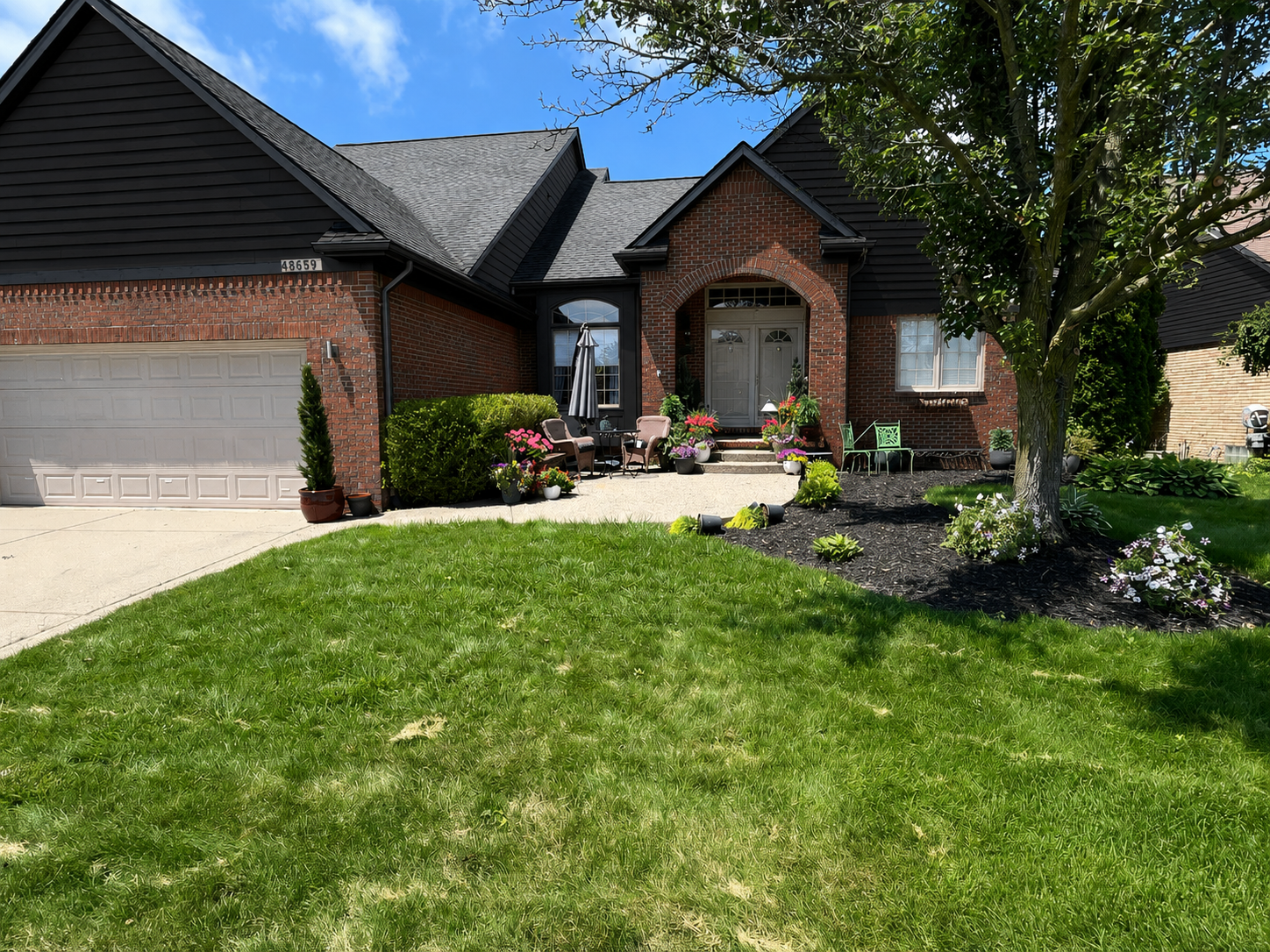 The same brick home after exterior painting with black siding, gables and trim